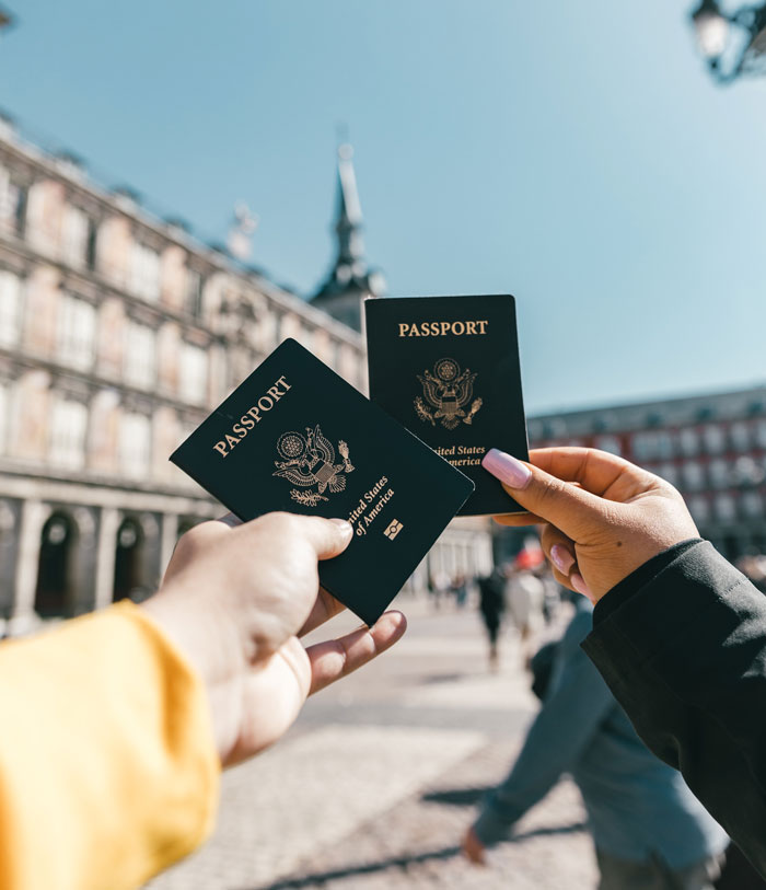 Person holding their passports in front of buildings