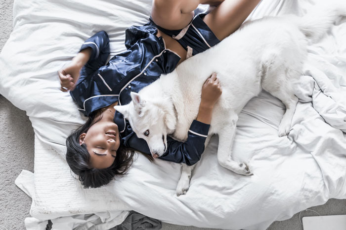 Woman lying on a bed with her dog 