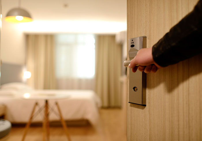 Person stands by the open door of hotel room