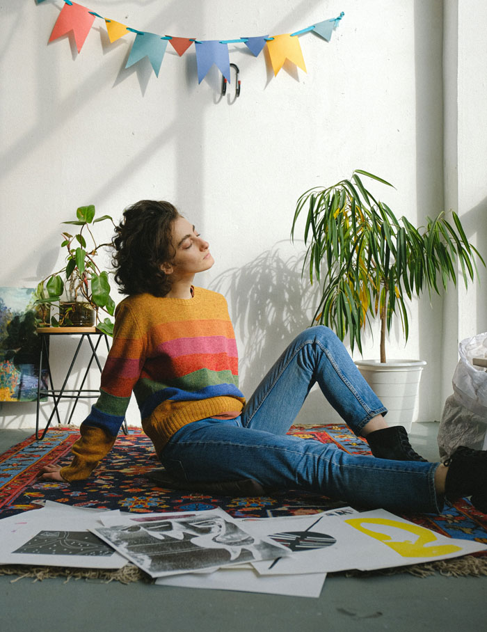 A young woman is sitting with drawings on a carpet and relaxing