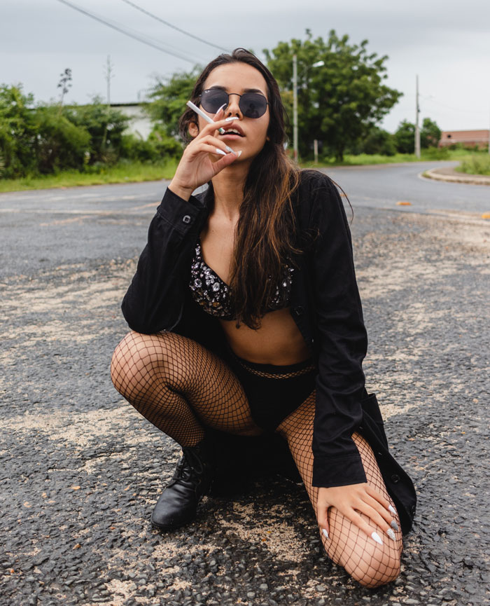 Woman in leather jacket posing and smoking a cigarette