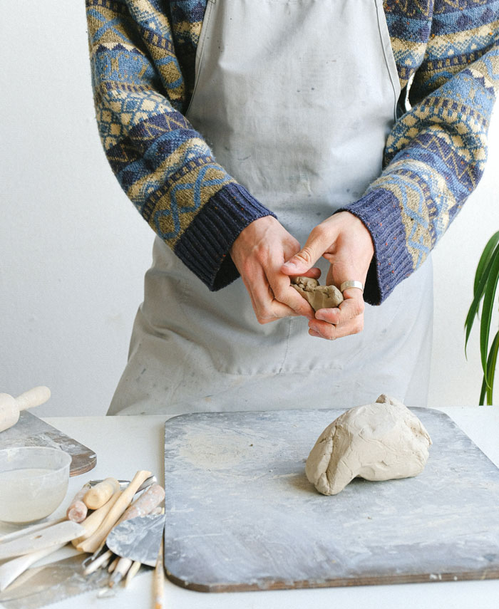 Man in a sweater and apron is sculpting