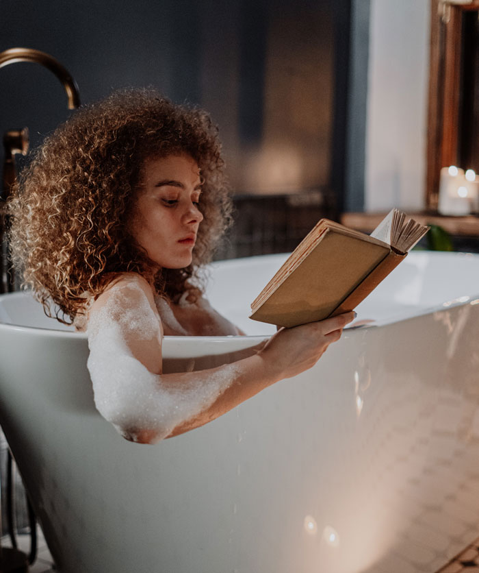 Woman reading a book in a bathtub 