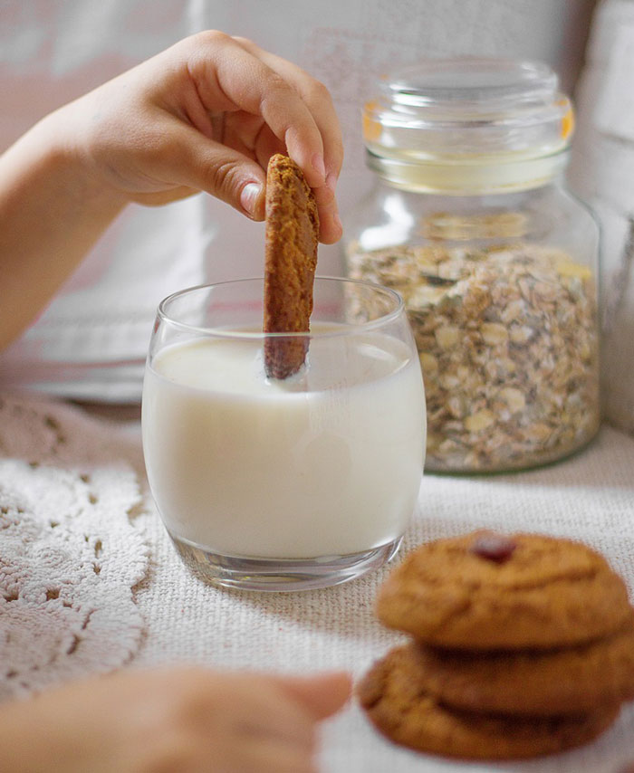 A kid dips cookie in milk