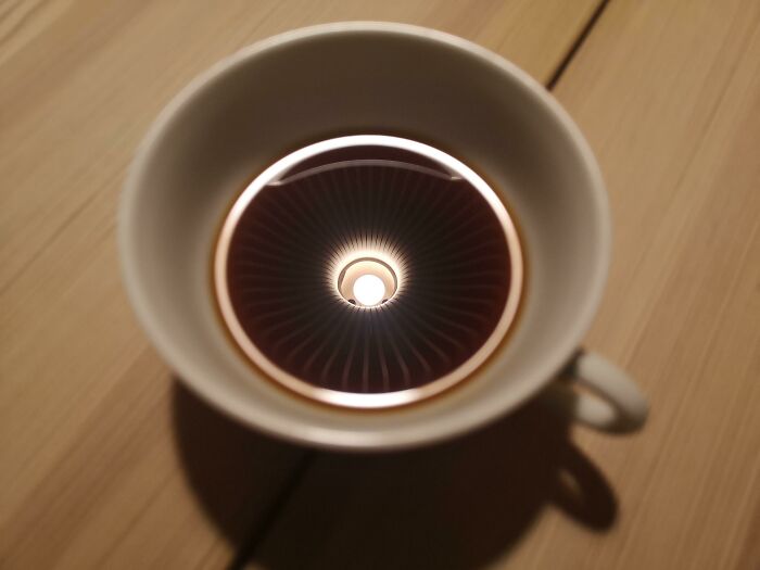 He tomado una foto de mi taza de café con el reflejo de una lámpara