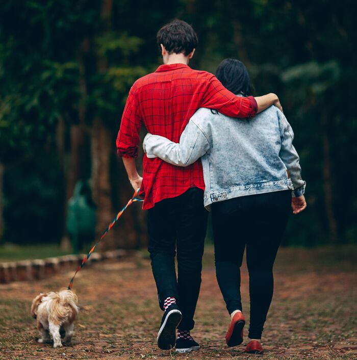 Couple Hugging And Walking Their Dog 