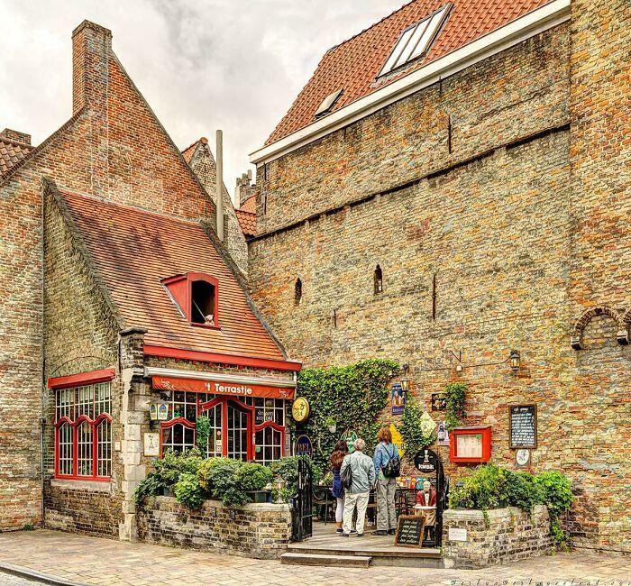 A Small Tavern Built Against The Wall Of One Of The Medieval Houses Of Oldtown Bruges. Brugge Is The Capital Of West Flanders, Belgium. Along With Other Canal-Based Northern Cities Such As Amsterdam And Stockholm, It Is Sometimes Referred To As The Venice Of The North