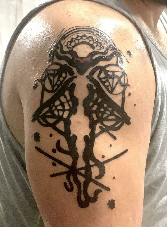 Marvel Wanda Vision tattoo design on upper arm, featuring bold black ink lines and geometric patterns.