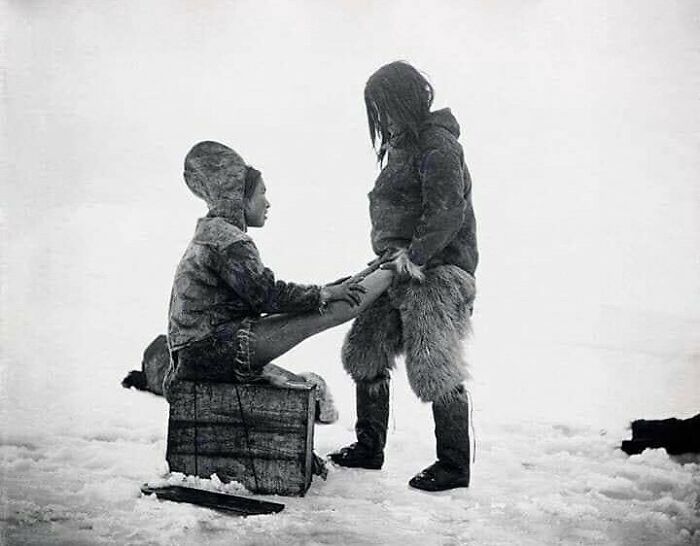 Un hombre inuit calienta los pies de su esposa. Groenlandia, 1890