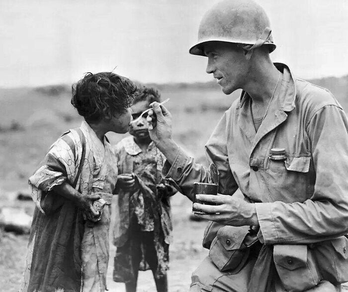 Un militar estadounidense comparte sus raciones con dos niños japoneses en Okinawa, 1945