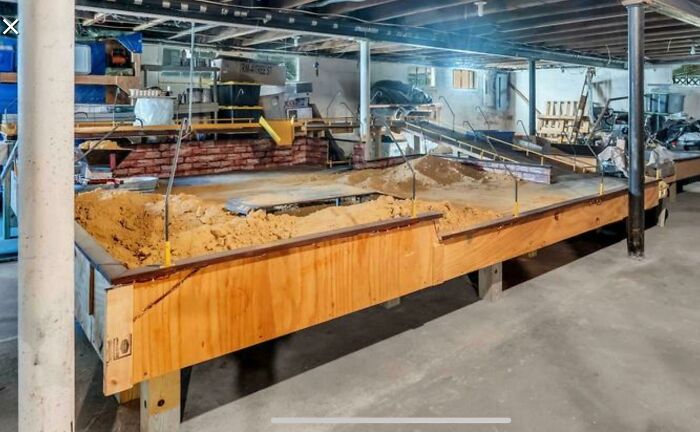 Large Sand Table In The Basement Of A House For Sale In Nj. More Than 10 Feet Long, Several Curved Metal Bars Or Tubes Around The Side And A "Bridge" In The Middle. On The Right In The Picture Is A Movable Conveyor Belt Thing. That's All The Info I Have