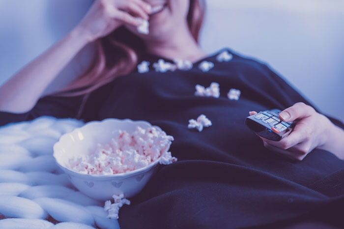 Woman with tv remote control watching a popcorn 