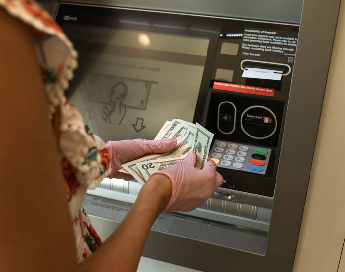 Person counting money in front of ATM