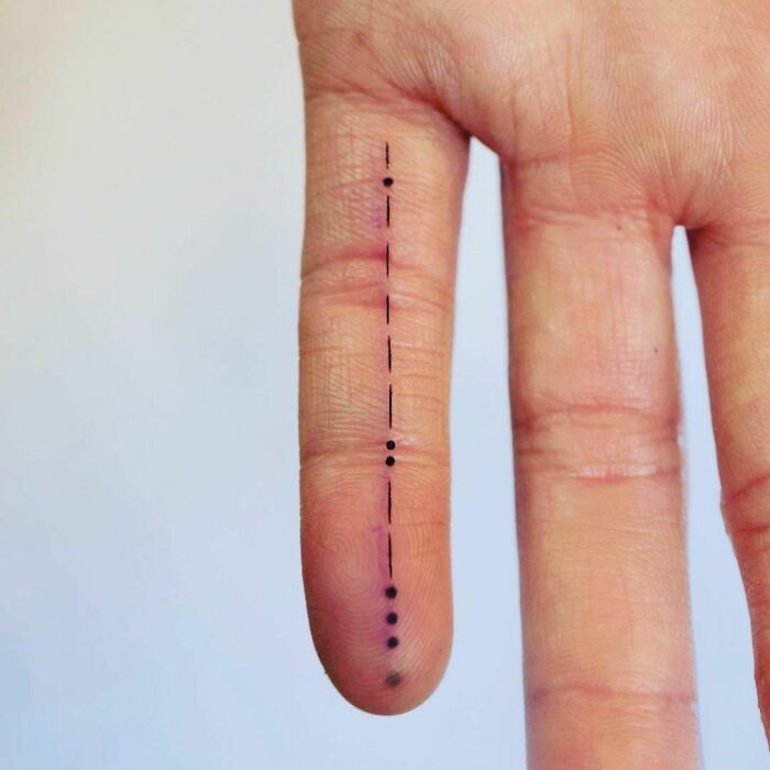 minimalistic tattoo of a morse code on finger