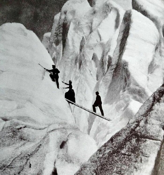 Late Victorian Mountaineers Cross A Crevasse In The Alps In The Year 1900. Apparently It Was A Fashion Crime To Be Caught Dead In Anything Other Than Your Finest Clothing, Even When Climbing Some Of The Worlds Most Treacherous Mountains
