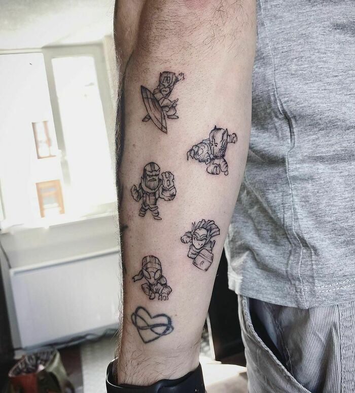 Marvel tattoos on forearm featuring mini superhero designs, showcasing unique artistic style in a casual setting.