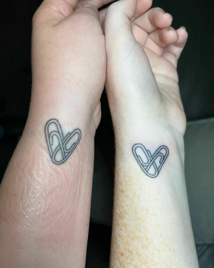 Matching heart-shaped tattoos on wrists symbolizing friendship.