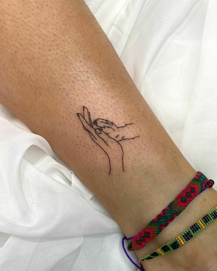 minimalistic tattoo of a paw and a hand