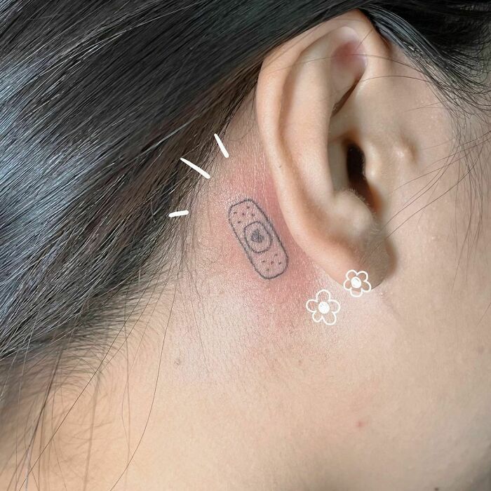 minimalistic tattoo of a bandage behind ear