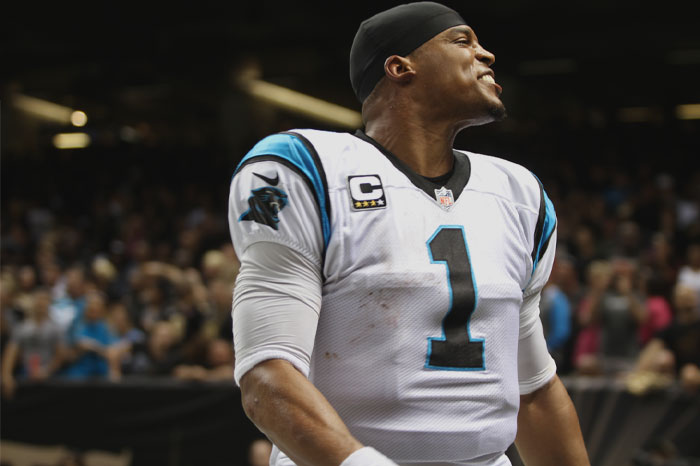 Cam Newton wearing American football clothes and smiling