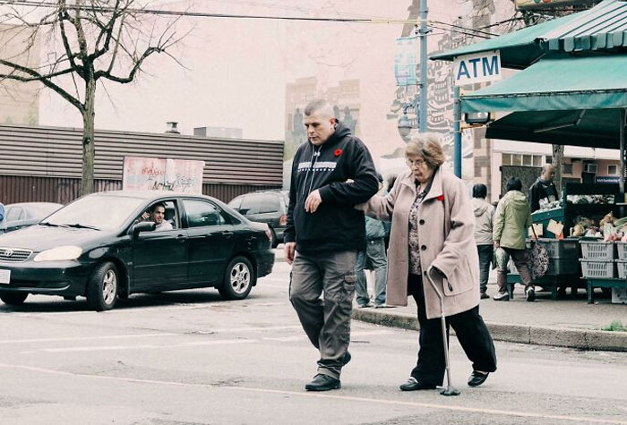 Man Helps Elderly Lady Cross A Street In Vancouver's Lower Income East Side
