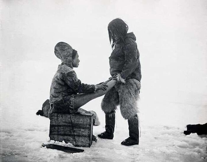 Un hombre inuit calienta los pies de su mujer, Groenlandia, 1890