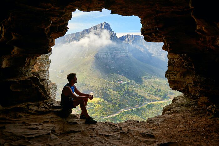 Man Sitting Outside Of A Cave In A Picturesque Place 