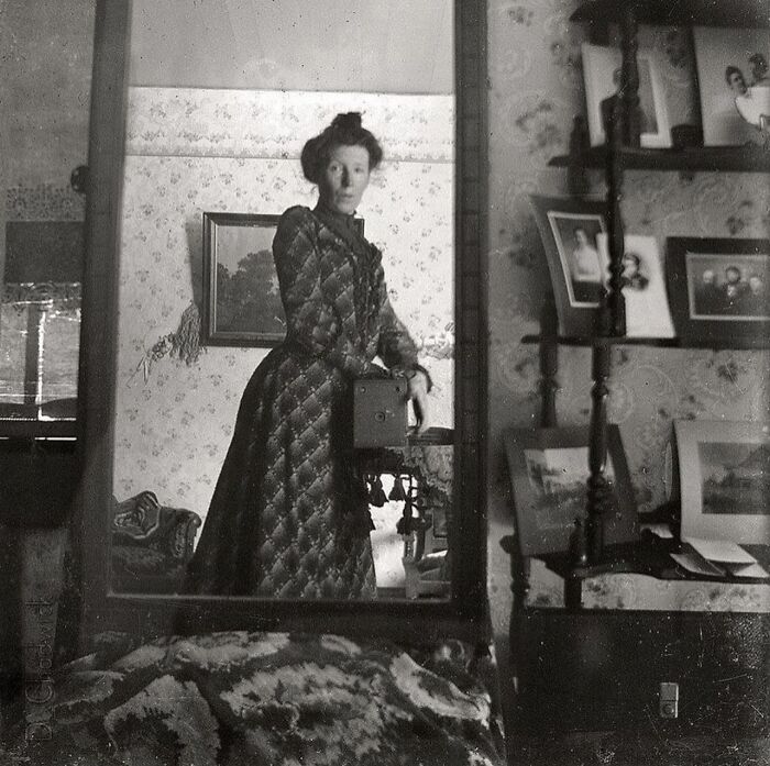 Una mujer tomándose una foto en 1900. La cámara que sostiene costaba 1 dólar