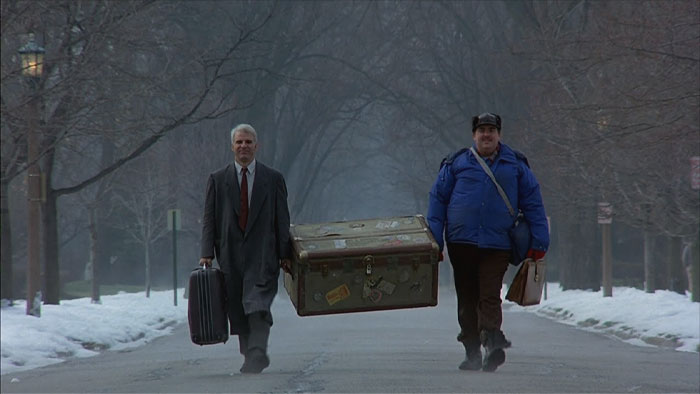 Two men in winter carrying a massive case 