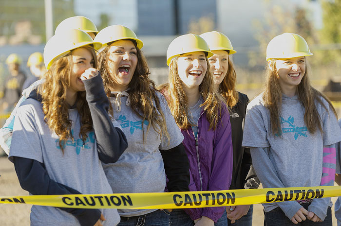 Womans wearing safety hats standing looking and smiling