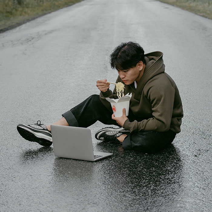 Person sitting eating ramen and watching