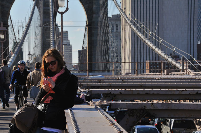 Woman standing and looking at the phone on the bridge