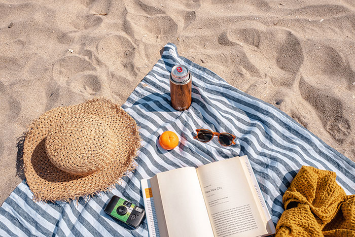 Books, sheet, phone and glasses on the beach