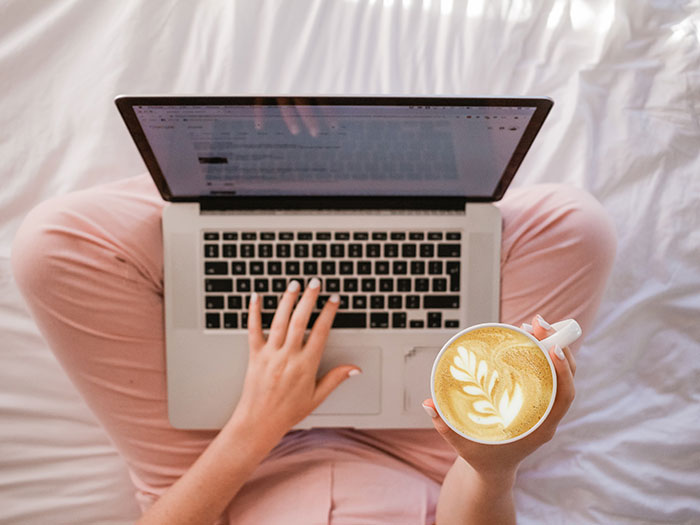 Woman looking at computer and holding coffee