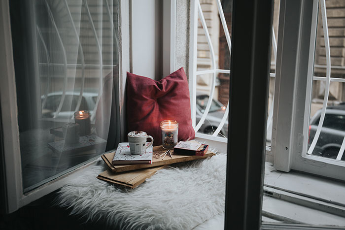 Picture of coffee, books and pillow near window