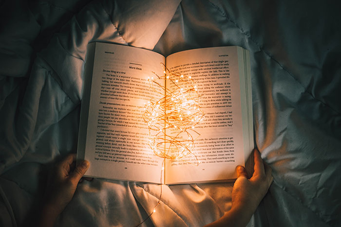 Person holding book with fairy lights