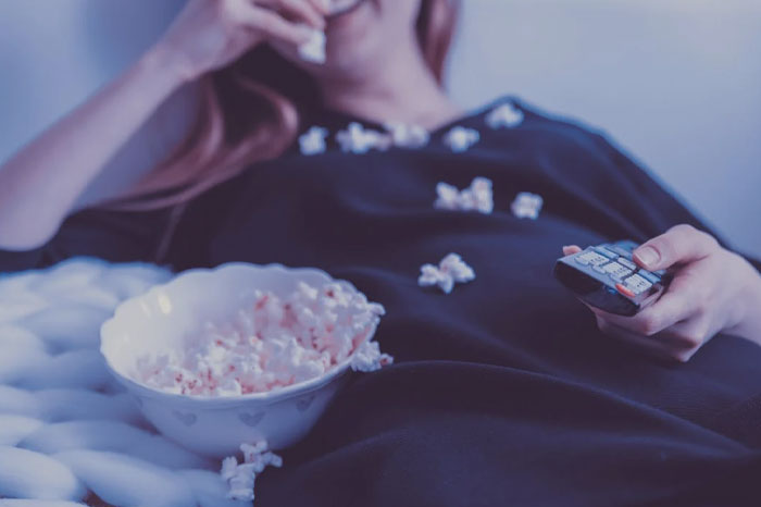 Person in bed eating popcorns 
