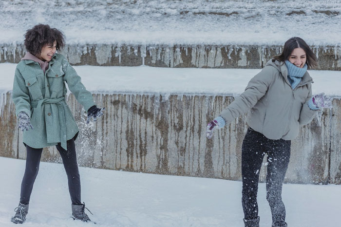 Two women playing snowball fight 