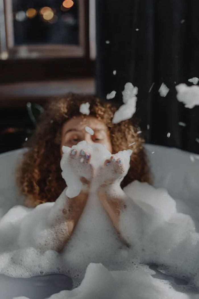 Woman in a bath blowing soap bubbles 