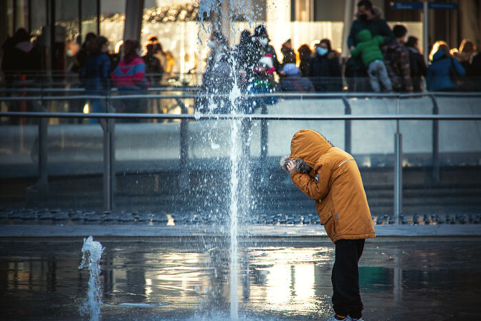 person standing next to a fountain wearing yellow jacket
