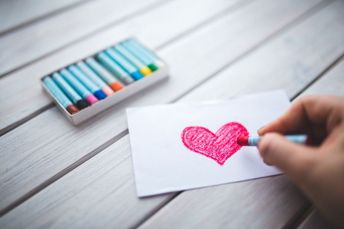 person drawing a red heart on the paper