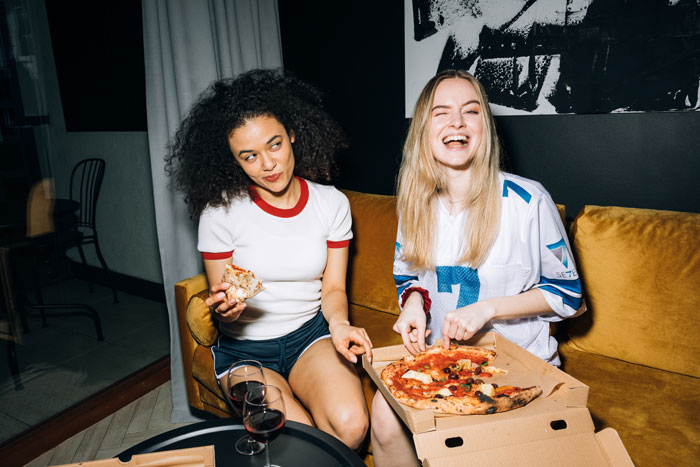 two girls smiling and eating pizza