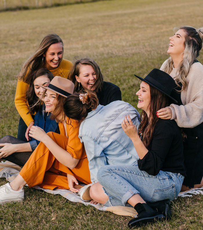 seven girls sitting on the ground and laughing