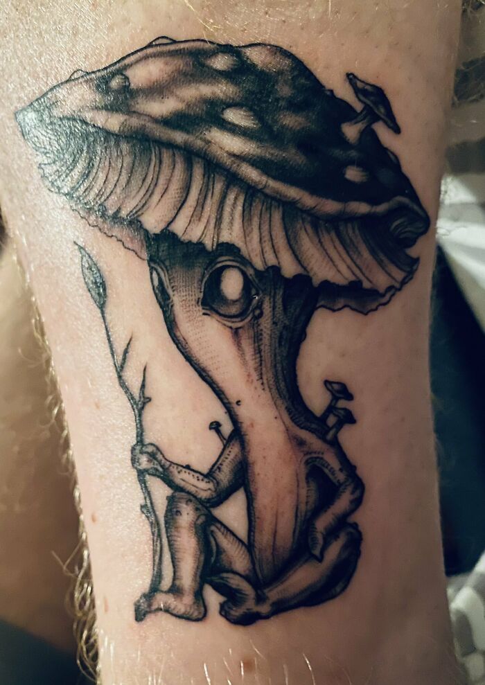 Mushroom character holding branch tattoo