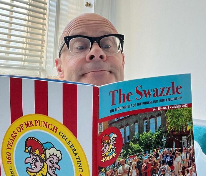 Bald man with glasses reading a magazine, representing the concept of smartest celebrities and intelligence.