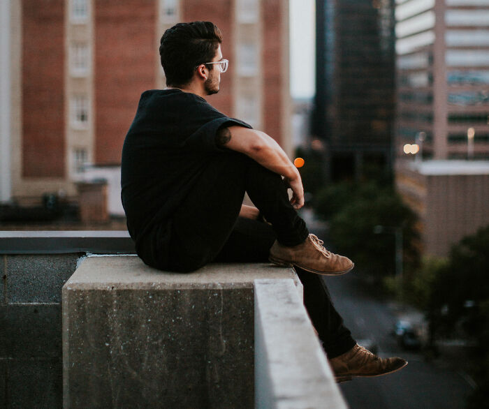 man wearing black shirt sitting on the roof 