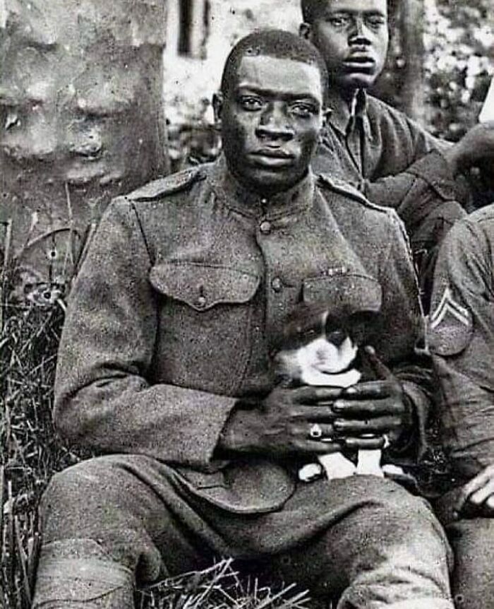 Un miembro de los Harlem Hellfighters (369º Regimiento de Infantería) posa para la cámara con un cachorro que salvó durante la Primera Guerra Mundial, 1918