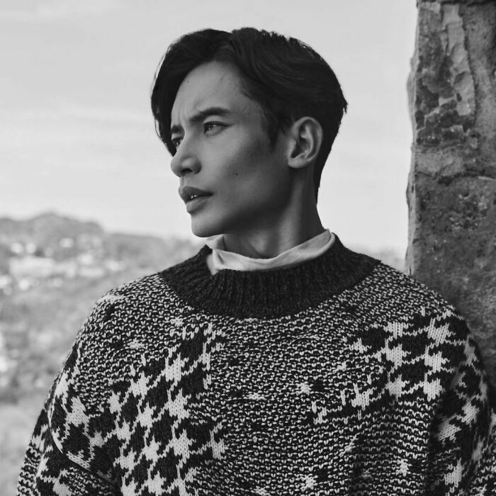 Black and white photo of a thoughtful celebrity wearing a patterned sweater, representing smartest celebrities and intelligence.