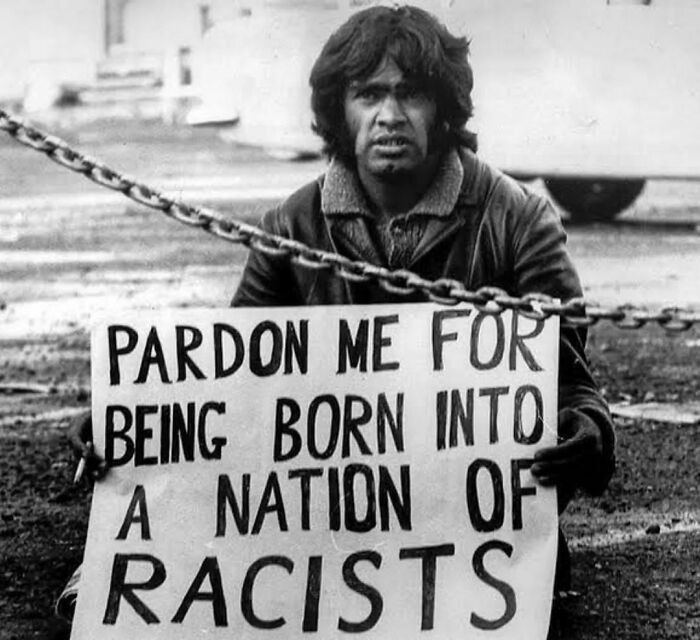 Imagen icónica que muestra al activista por los derechos de los aborígenes Gary Foley con un cartel en el que se lee: "Perdónenme por haber nacido en una nación de racistas", 1971