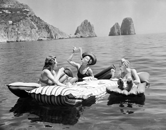 Tres jóvenes comen espaguetis en colchones inflables en la isla de Capri, 1939